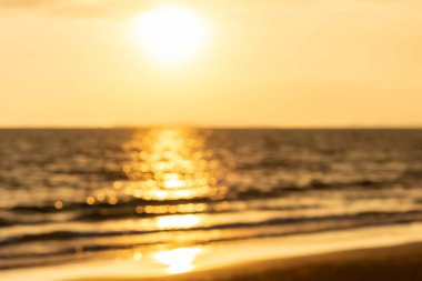 Güneşin suyun üzerinde ışıl ışıl parladığı, ılık bir zemin için altın deniz ve kumdan oluşan, deniz üzerindeki bulanık günbatımı manzarası ılık ve rahatlatıcı bir atmosfer yaratıyor. Barışçıl ve doğal hissetmek için ideal