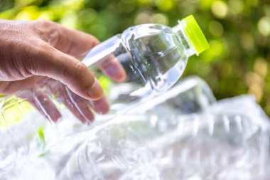 Plastik atık, boş bir plastik şişeyi tutan, plastik atık sorununu sembolize eden, atık yönetimi çabaları ve plastik atıkların azaltılmasına yönelik farkındalık