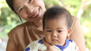 Annesiyle oynayan yakın plan bebek mutlu kucaklaşmalar, Tayland 'lı genç anne parkta bebeği tutuyor, mutlu aile çocuğu yaşam tarzı rüya kavramı.