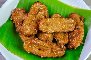 Beyaz bir tabakta muz yaprağında servis edilen kızarmış Tayland muzu, tatlı ve çıtır çıtır dokulu geleneksel Asya atıştırmalığıdır. Üst görünüm yakın çekim