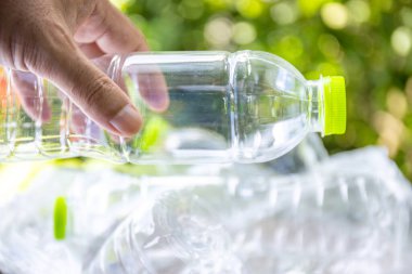 Plastik atık, boş bir plastik şişeyi tutan, plastik atık sorununu sembolize eden, atık yönetimi çabaları ve plastik atıkların azaltılmasına yönelik farkındalık