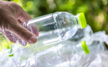 Plastik atık, boş bir plastik şişeyi tutan, plastik atık sorununu sembolize eden, atık yönetimi çabaları ve plastik atıkların azaltılmasına yönelik farkındalık