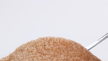 brown sugar, spoon scooping granulated brown sugar, symbolizing excessive sugar consumption, diabetes and health risks, health awareness, sugar for sweetness food, ingredient dessert