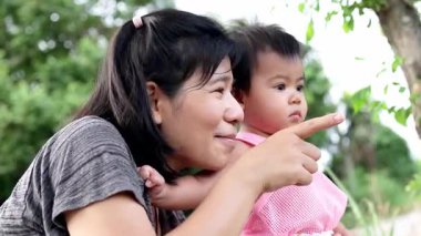 Anne kucağında bir gülümsemeyle, sevgisini, sıcaklığını ve neşe dolu aile anlarını gösteriyor.