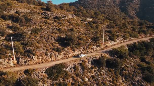 白色轿车在山体斜坡上狭窄的道路上行驶时的空中跟踪目标 — 图库视频影像