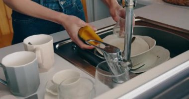 Kadın eli, pencerenin yanındaki lavaboda bulaşık yıkıyor.