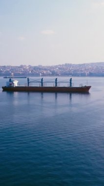 Kargo gemisi demirleme yerinde bekliyor. İskele tarafında yükleniyor. Geniş açı.