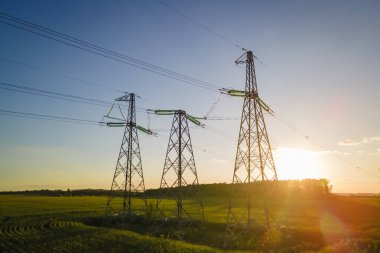 Elektrik altyapısı iletim kuleleri kırsal alanda günbatımı gökyüzü arka planı, hava manzarası