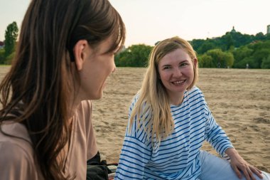 Günlük giysiler içinde genç bayan arkadaşlar plaj tatilinde pikniğin tadını çıkarıyorlar.