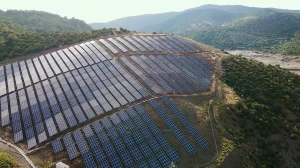 太陽光発電所の太陽光発電所パネルを日没時に山の風景に連続して眺める — ストック動画