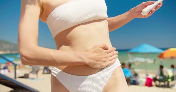 女性は公共のビーチで体に日焼け止めソーラークリームUv保護を適用します クローズアップ — ストック動画