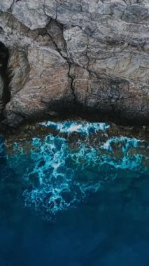 Üst manzara okyanus mavi dalgaları resiflerin sahil şeridi drone görüntülerine çarpar. Dikey çekim