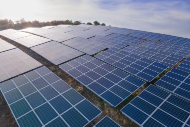 Güneş enerjisi santralinin panellerini günbatımında yeşil enerji, ekolojinin yenilikçi doğa ortamı alanlarında art arda kapatın. Hava görüntüsü