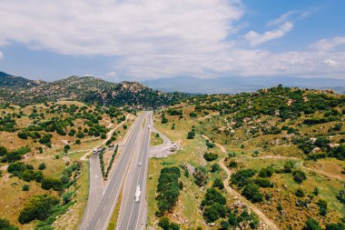 Güneşli bir günde dağların arasından geçen trafik otoyolunun havadan görünüşü