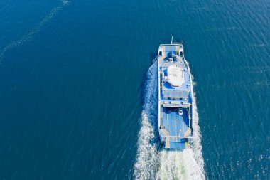 Feribot güvertede araçları taşıyor, hava manzaralı.