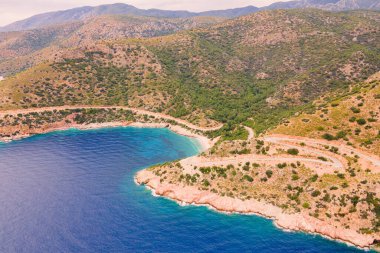 Tepeler ve deniz manzarası arasında dolambaçlı yol, havadan çekim