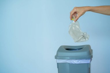 Kadın çöp kutusuna plastik şişe koyuyor, atık toplama ve geri dönüşüm konseptini ayırıyor.