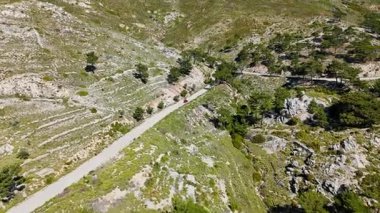 Araba manzarası sakin ve çorak tepeler ve dağların arasından dolambaçlı yol geçiyor, Yunanistan