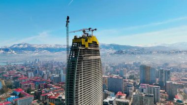 İnşaat sahasında arka planda dağlara karşı çalışan vinçler, Aerial view