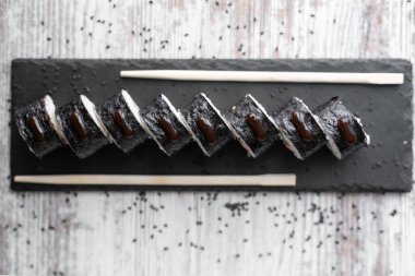 Hafif somon balığı filadelfiya. Siyah masa üstünde soğan. Yemek çubuğuyla beyaz arka plan.