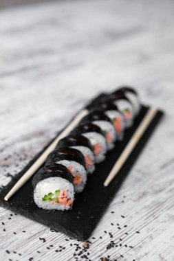 Hafif somon balığı filadelfiya. Siyah masa üstünde soğan. Yemek çubuğuyla beyaz arka plan.