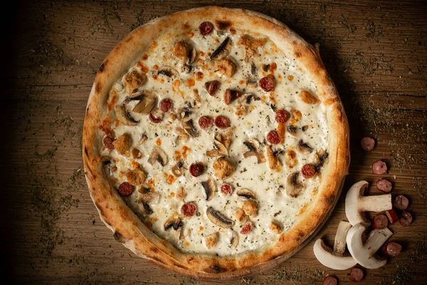 delicious chicken pizza with sausages and mushroom. dark wooden table background low key