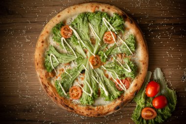 Salata yapraklı ve kiraz domatesli leziz tavuk pizzası. koyu tahta masa arkaplanı alçak tuş