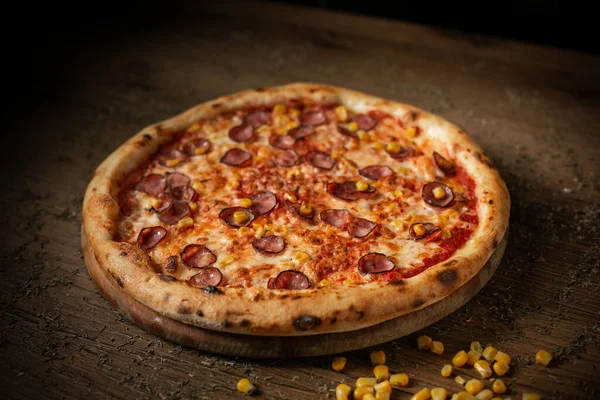 Sosisli domates pizzası ve mısır esmer ahşap masa arka planı sade.