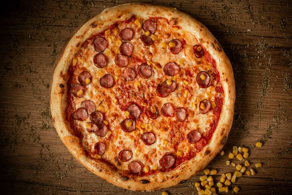 delicious tomato pizza with sausages and corn dark wooden table background low key