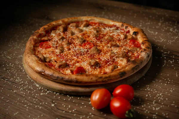 delicious pizza with chicken and cherry tomatoes, sprinkled with sesame seeds, dark wooden table background low key