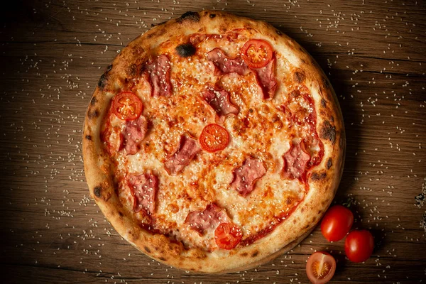 Tavuk ve kiraz domatesli lezzetli pizza, susam tohumları serpiştirilmiş, üst manzara. koyu tahta masa arkaplanı alçak tuş