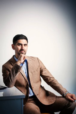 Çekici iş adamı kamerası bir ofis elbisesine bakıyor ve oturuyor.