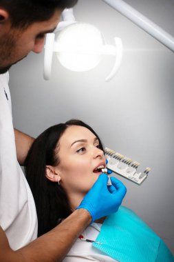 Diş hekimindeki hasta aynadaki dişlerine bakar, diş paletindeki dişlerin rengini seçer.