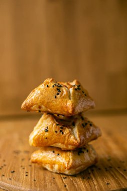 Tahta arka planda izole edilmiş beyaz yuvarlak bir tabakta chiken ile dört adet yenilebilir kare puf böreği sepeti. yan görünüm