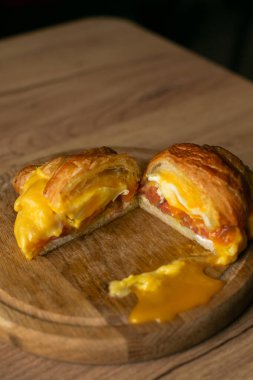 Tahta tabakta omletli büyük lezzetli somon kruvasanı. Arka planda ahşap. Yakın plan görüntüsü.