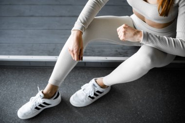 Beyaz spor giyen formalı kız spor salonunda oturuyor. üst görünüm