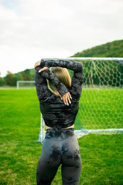 Stadyumda esneme hareketleri yapan siyah spor giysili fit bir kızın fotoğrafı spor esneme egzersizleri yaptırıyor..