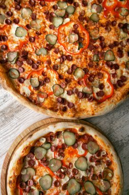 Ahşap masada çeşitli soslu ve peynirli iki farklı lezzetli pizza. en üstteki görünüm