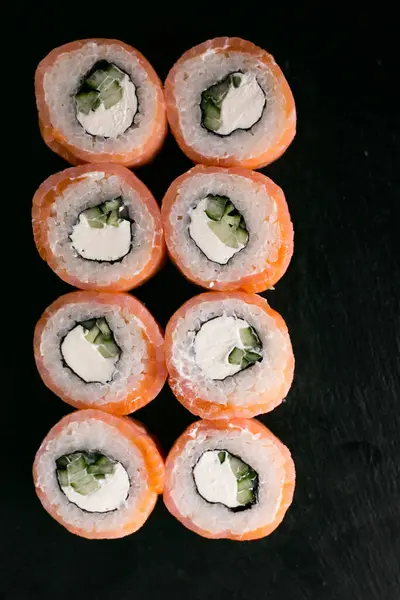 light salmon sushi philadelphia with onion on black desk background with chopstick