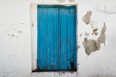 Yıpranmış mavi ahşap panjurlar ve hasarlı duvar