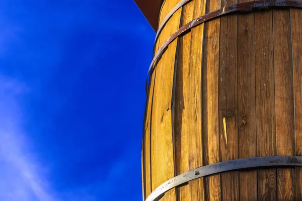 Close-up of a wooden keg against a deep blue sky on a sunny day, handmade keg with metal hoops outdoors, copy space, background image
