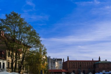 Sonbahar gökyüzü sinagog, sonbahar ağaçları ve Polonya 'nın Yahudi mahallesindeki eski evler, arka planda Kazimierz' de bir sonbahar akşamında klasik sinagog binası olan şehir manzarası.