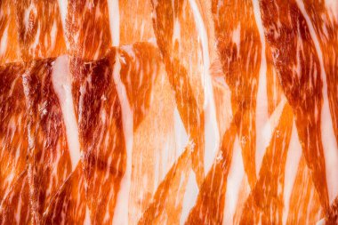 İspanyol jamonunun lezzetli et dilimlerinin soyut arka planı, arka plan ve ekran koruyucu için yakın plan jamon iberico (serrano jambon) dilimleri, ince et dilimleri dokusu. düz düz