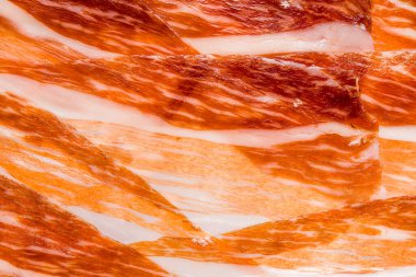 İspanyol jamonunun sulu et dilimlerinin yakın çekimi, arka plan ve ekran koruyucu için soyut iberico jambonu dilimleri (serrano jambonu), ince et dilimleri dokusunun makro fotoğrafı, düz uzanmış