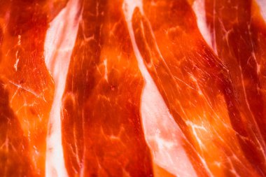 Ekran koruyucu ve arkaplan için soyut İspanyol jamonu dilimleri, Iberico jamon 'un sulu et dilimlerinin (serrano jamonu) yakın plan çekimi, ince et dilimlerinin makro resmi, düz konum