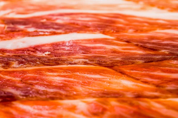 Arka plan ve ekran koruyucu için Iberico jamon (serrano jamonu) dilimlerinin soyut deseni, İspanyol jamonun sulu et dilimlerinin yakın çekimi, ince et dilimlerinin dokusunun makro fotoğrafı, düz uzanmış