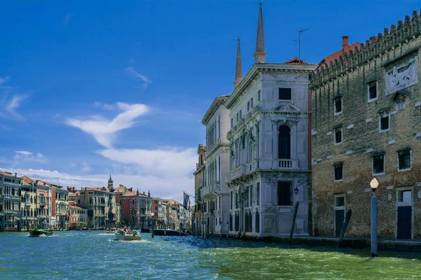 威尼斯市的大运河 阳光灿烂的早晨 威尼斯一条宽阔的街道上的老式房屋 小船和贡多拉漂浮在翡翠的水面上 威尼斯房屋上方的蓝天 游客在意大利旅行 — 图库照片