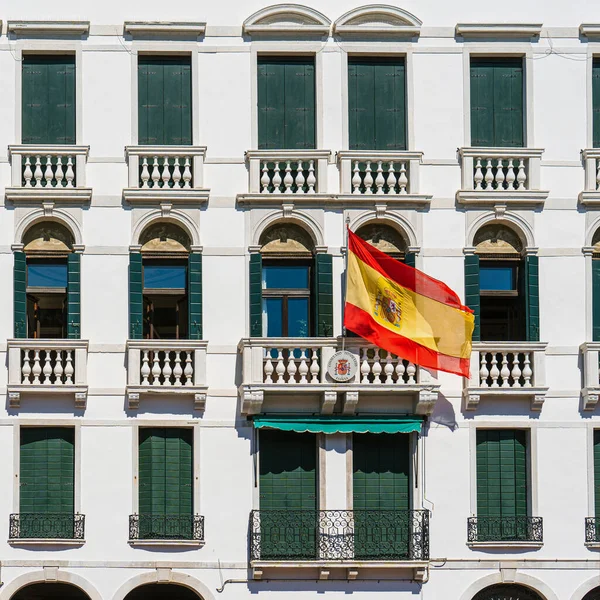 Spanish flag on the wall of the building of the Spanish Consulate in the city of Venice on a sunny day. The flag of Spain flutters in the wind on the balcony of the Spanish consulate