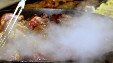 Açık havada, geleneksel et yemekleri bir caddede büyük bir kızartma tavasında pişiriliyor. Bir şef, Krakow 'daki Noel pazarında büyük bir tavada geleneksel et yemekleri hazırlıyor.