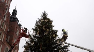 Kamu çalışanları uzun bir şehir ağacını Noel 'den önce Polonya' nın Krakow kentindeki bir sokakta Noel oyuncaklarıyla süslüyor. Polonya 'nın Noel ve Yeni Yıl kutlamalarının otantik sahnesi